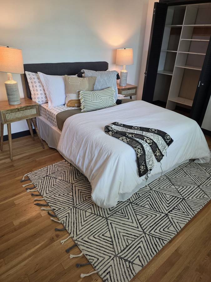 Bedroom with a made bed, bedside lamps and a patterned rug