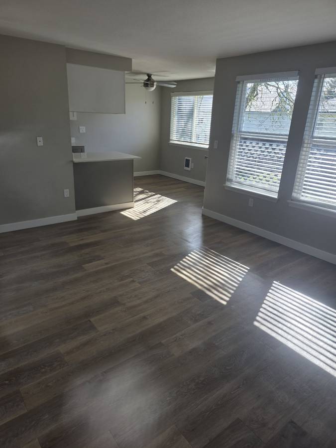 Empty living space with wood floors and large windows