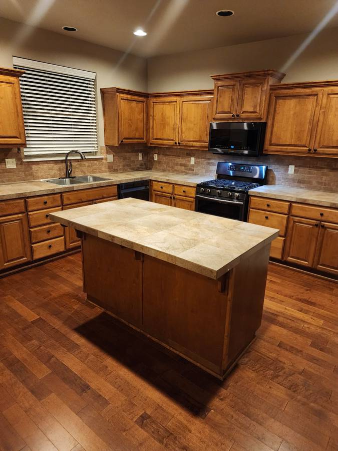 Kitchen with wood cabinets, an island counter and wood floors
